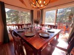 Seating for 8 at the dining table with large windows boasting the outdoor pines and mountains